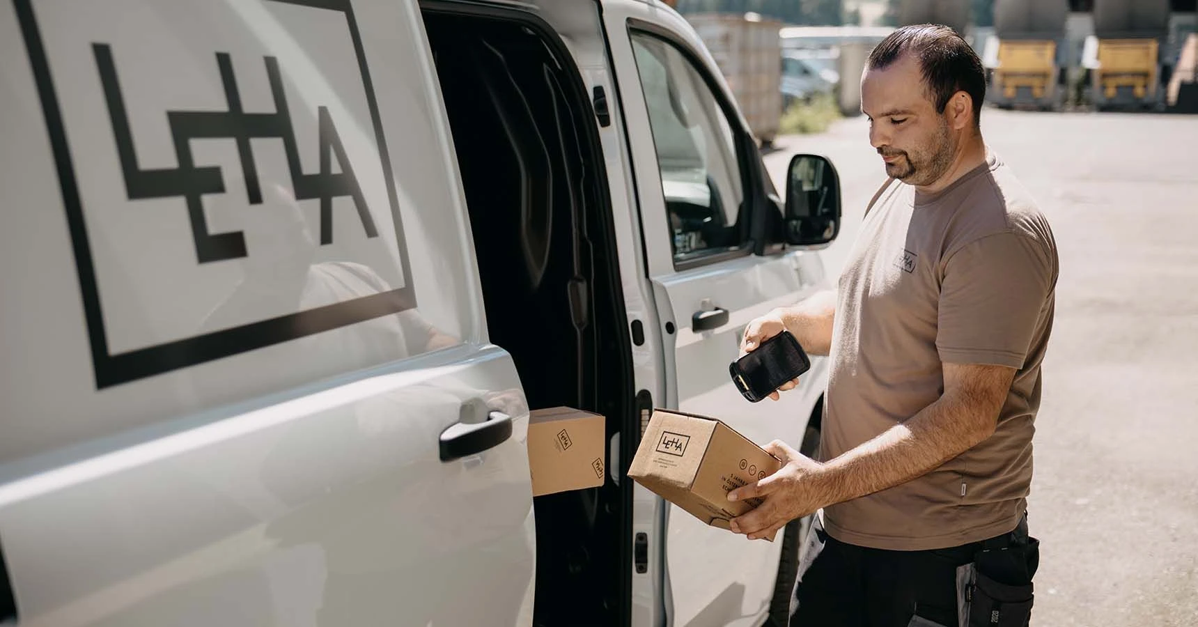 LEHA Zusteller scannt mit mobilem Computer ein Paket