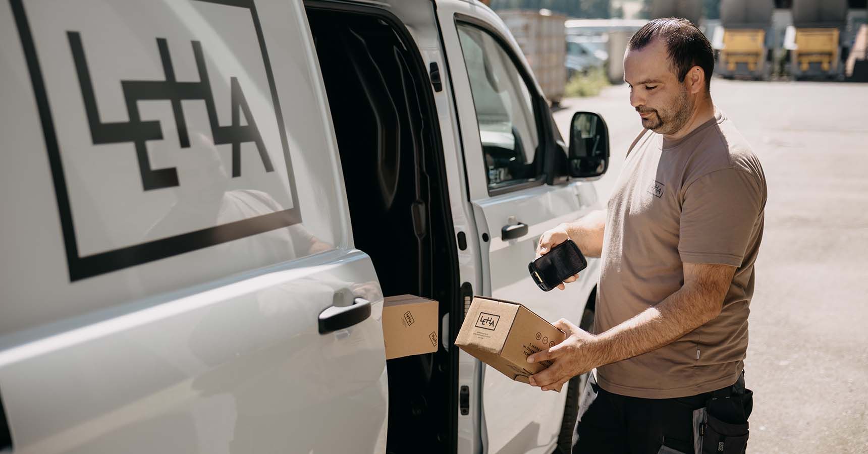 LEHA Zusteller scannt mit mobilem Computer ein Paket