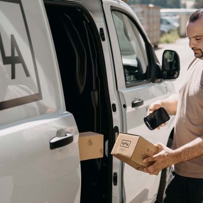 LEHA Zusteller scannt mit mobilem Computer ein Paket